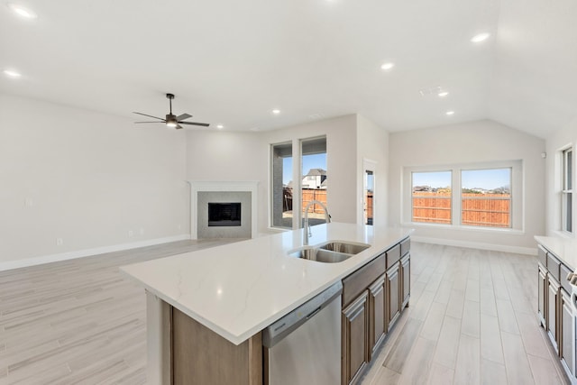 kitchen featuring dishwasher, light wood-type flooring, a center island with sink, and sink