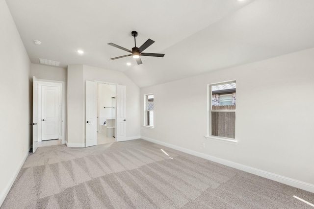 unfurnished bedroom featuring connected bathroom, ceiling fan, light carpet, and vaulted ceiling