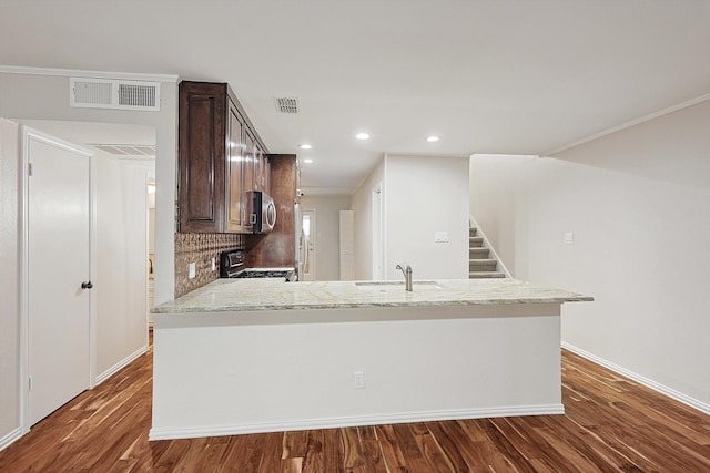 kitchen featuring backsplash, sink, dark hardwood / wood-style floors, light stone countertops, and stainless steel appliances