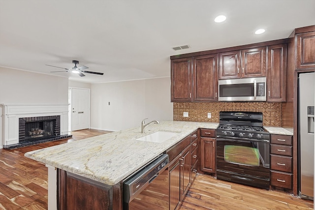 kitchen featuring kitchen peninsula, tasteful backsplash, sink, black appliances, and light hardwood / wood-style floors