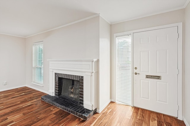 entryway with hardwood / wood-style flooring, crown molding, and a brick fireplace