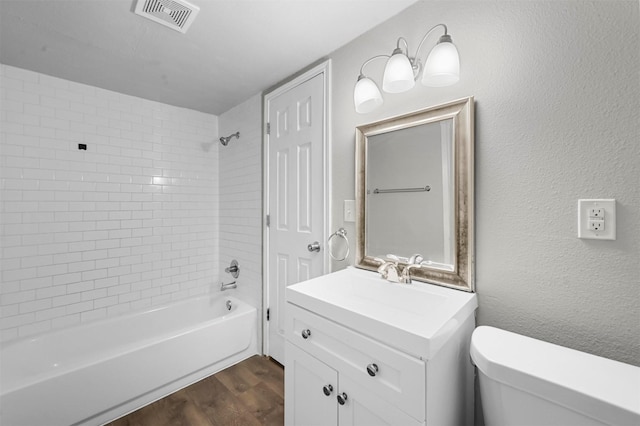 full bathroom with vanity, wood-type flooring, tiled shower / bath combo, and toilet