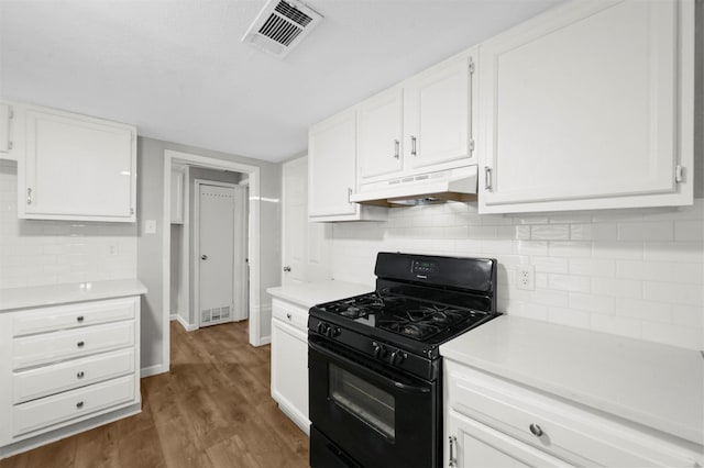 kitchen featuring dark hardwood / wood-style floors, gas stove, decorative backsplash, and white cabinetry