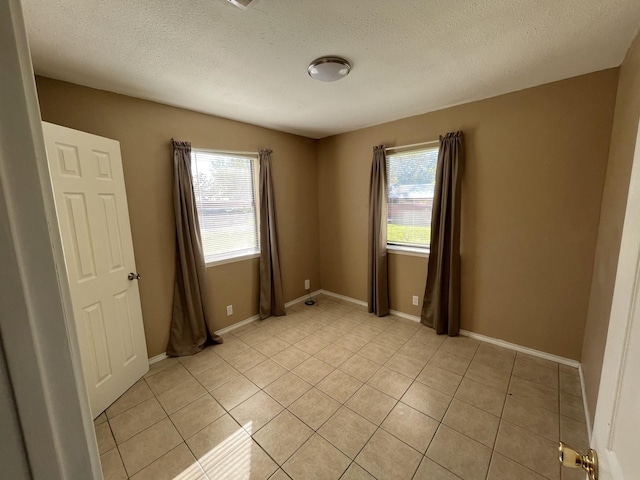 tiled empty room with a textured ceiling and plenty of natural light