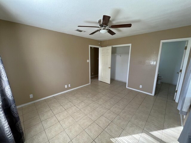 unfurnished bedroom with ensuite bath, ceiling fan, a closet, and light tile patterned flooring