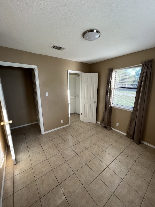 unfurnished bedroom featuring light tile patterned floors, a textured ceiling, and a closet