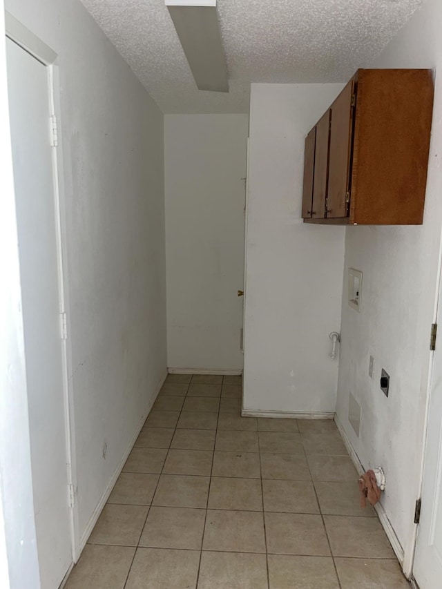 clothes washing area featuring hookup for an electric dryer, washer hookup, cabinets, a textured ceiling, and light tile patterned floors