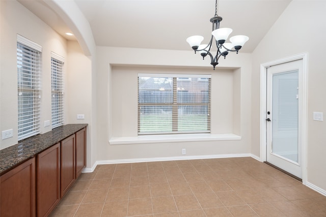 unfurnished dining area featuring vaulted ceiling, light tile patterned flooring, and a chandelier