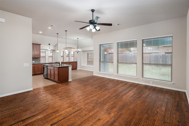 kitchen with hanging light fixtures, dishwasher, a kitchen island with sink, and a wealth of natural light