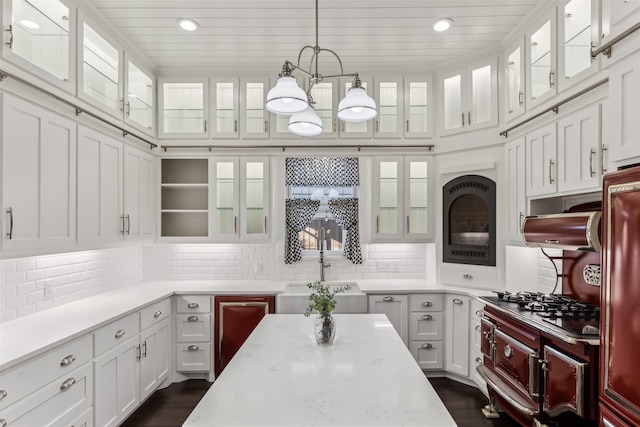 kitchen with pendant lighting, white cabinets, sink, light stone countertops, and dark hardwood / wood-style flooring