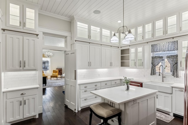 kitchen with sink, a chandelier, hanging light fixtures, a kitchen island, and white cabinets