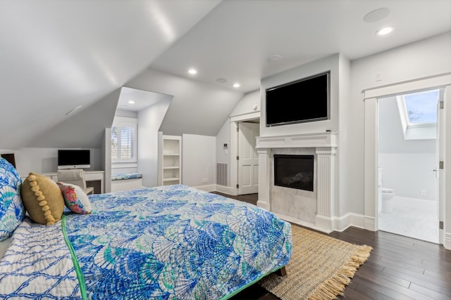 bedroom with lofted ceiling, connected bathroom, and dark hardwood / wood-style floors