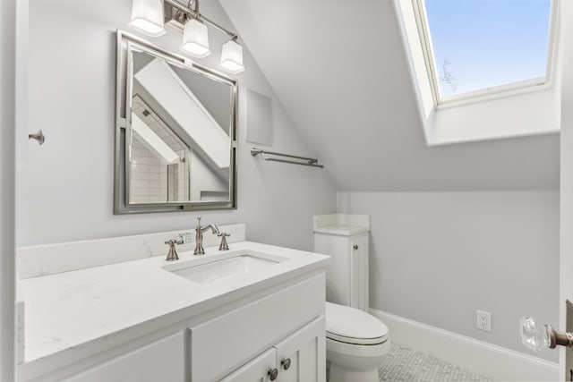 bathroom with toilet, vanity, and lofted ceiling with skylight