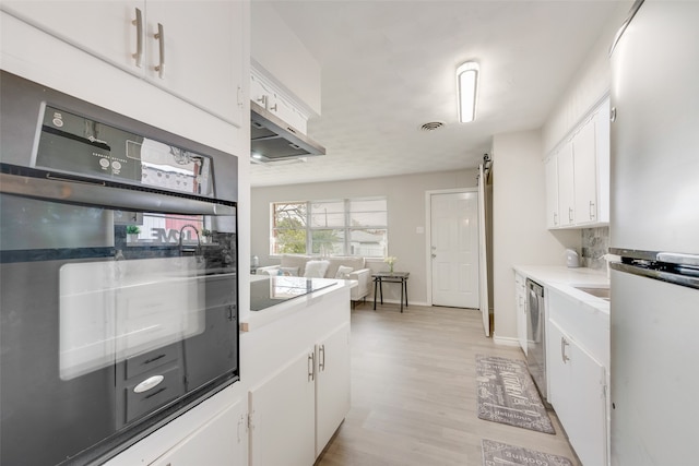 kitchen with white cabinets, black appliances, and light hardwood / wood-style flooring