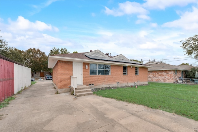 rear view of house featuring solar panels and a yard