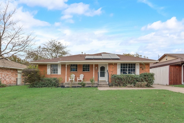 single story home featuring solar panels, a porch, and a front lawn