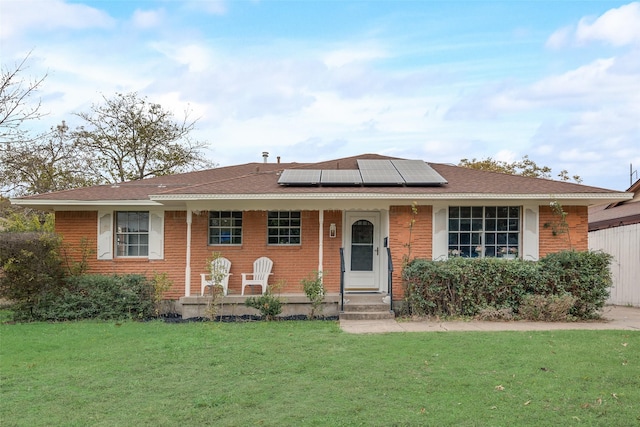 ranch-style home featuring a front lawn, covered porch, and solar panels