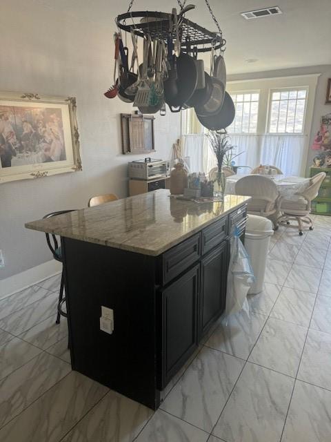 kitchen featuring a breakfast bar, light stone countertops, and a kitchen island