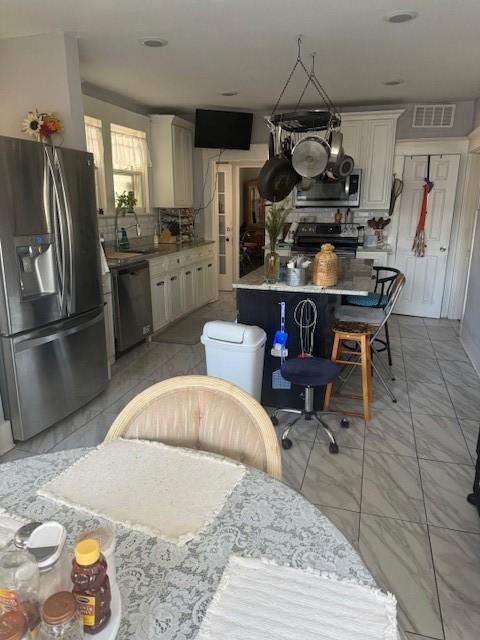 kitchen with sink, stainless steel appliances, a center island, tasteful backsplash, and cream cabinetry