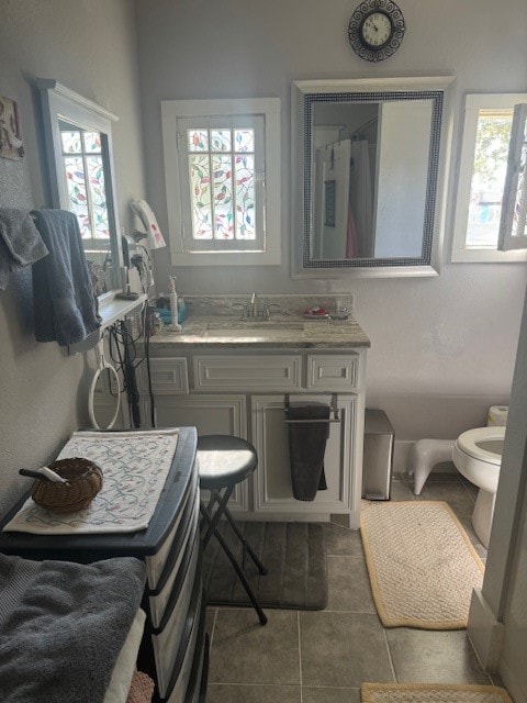 bathroom featuring vanity, a healthy amount of sunlight, tile patterned floors, and toilet