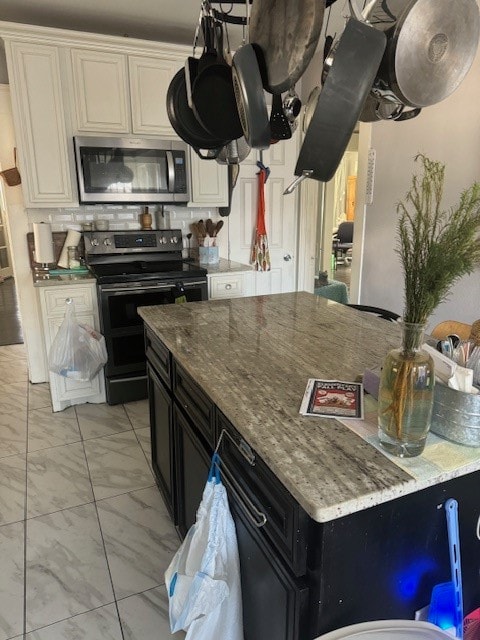 kitchen featuring backsplash, light stone countertops, electric range oven, and white cabinets