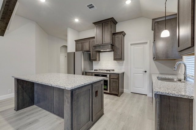 kitchen featuring a kitchen island, appliances with stainless steel finishes, pendant lighting, sink, and light wood-type flooring