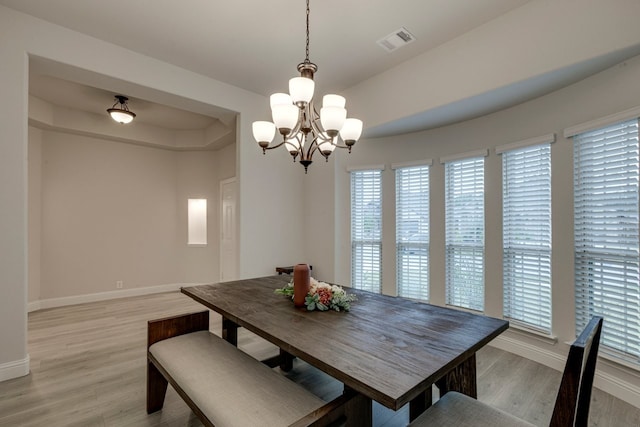 dining room with an inviting chandelier, a tray ceiling, and light hardwood / wood-style floors