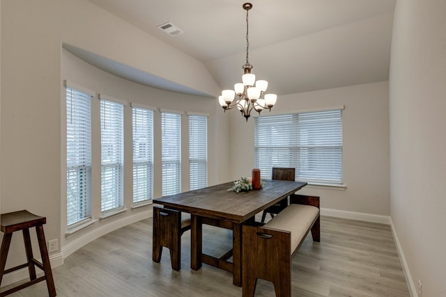 dining room with an inviting chandelier, vaulted ceiling, and light wood-type flooring