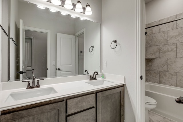 full bathroom featuring vanity, tiled shower / bath, and toilet