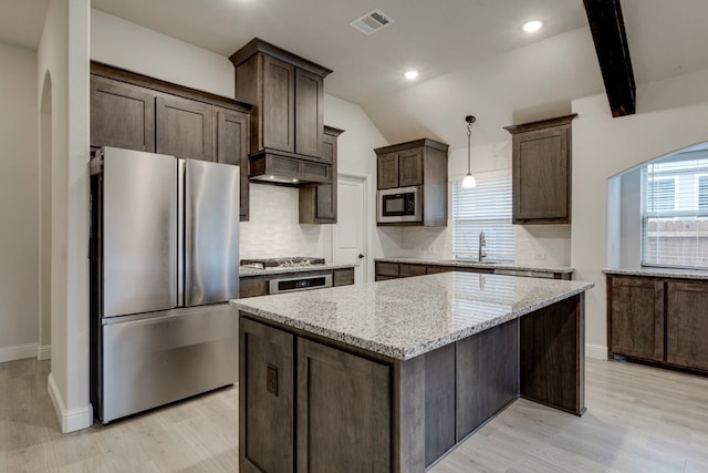 kitchen with premium range hood, appliances with stainless steel finishes, decorative light fixtures, a center island, and light stone countertops