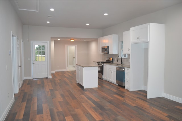 kitchen with white cabinets, stainless steel appliances, a kitchen island, and sink