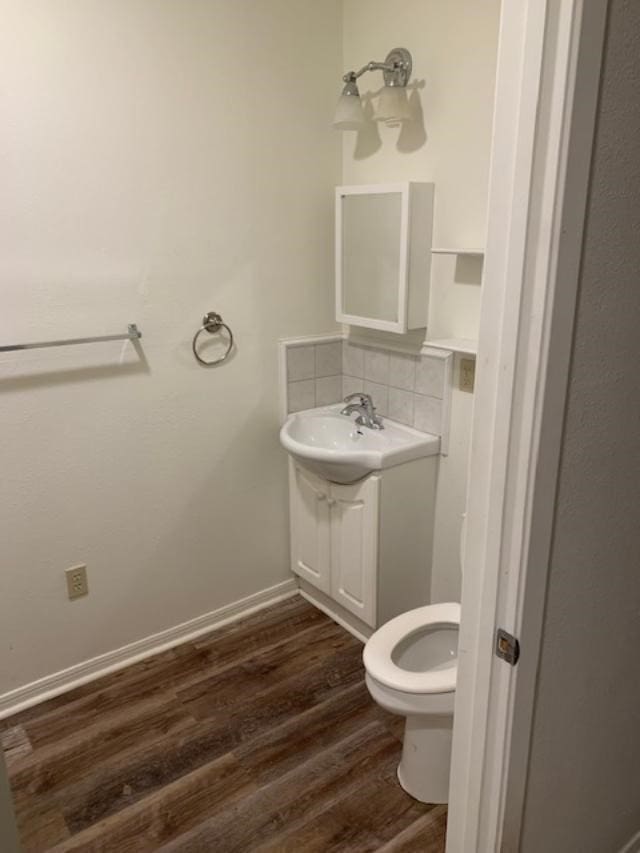 bathroom with backsplash, toilet, sink, and hardwood / wood-style flooring