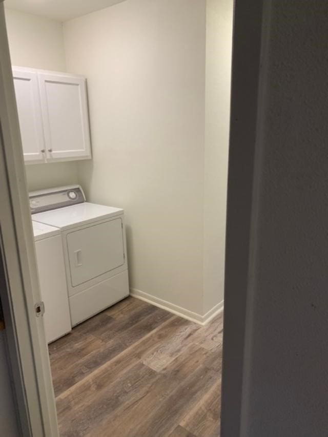 laundry area with cabinets, dark hardwood / wood-style flooring, and washing machine and dryer