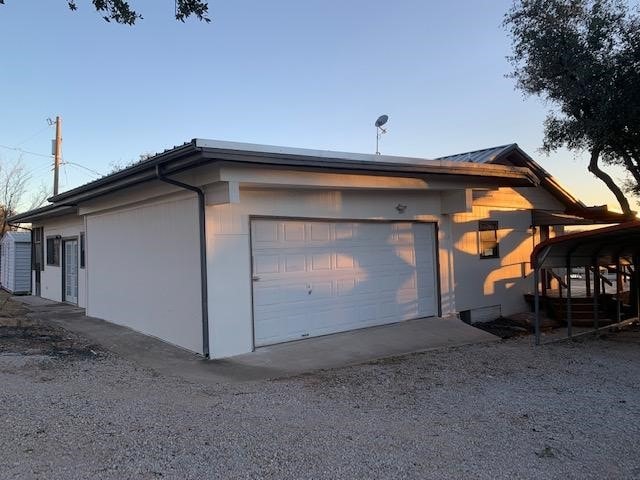 garage at dusk with a carport