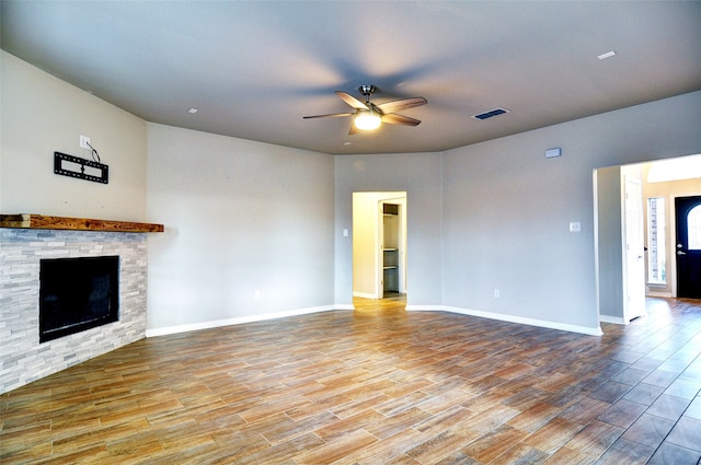 unfurnished living room with light hardwood / wood-style floors, a stone fireplace, and ceiling fan