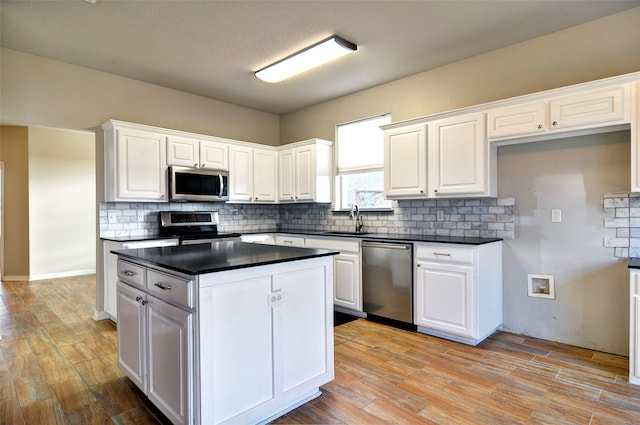 kitchen with sink, stainless steel appliances, decorative backsplash, white cabinets, and light wood-type flooring