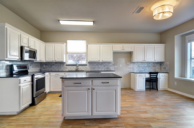 kitchen with decorative backsplash, stainless steel appliances, and white cabinetry