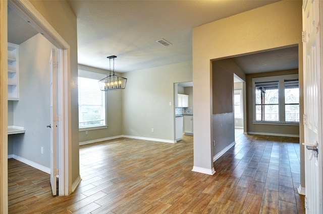 unfurnished dining area with hardwood / wood-style floors, a notable chandelier, and a wealth of natural light