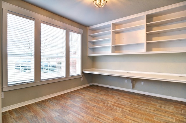 unfurnished office with a healthy amount of sunlight, wood-type flooring, and ornamental molding