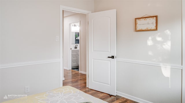 bedroom with wood-type flooring, ensuite bath, and sink