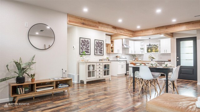 kitchen featuring dark hardwood / wood-style floors, beam ceiling, white cabinetry, and hanging light fixtures