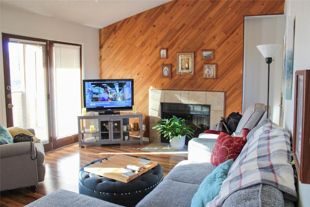 living room featuring hardwood / wood-style flooring, a tile fireplace, and wood walls