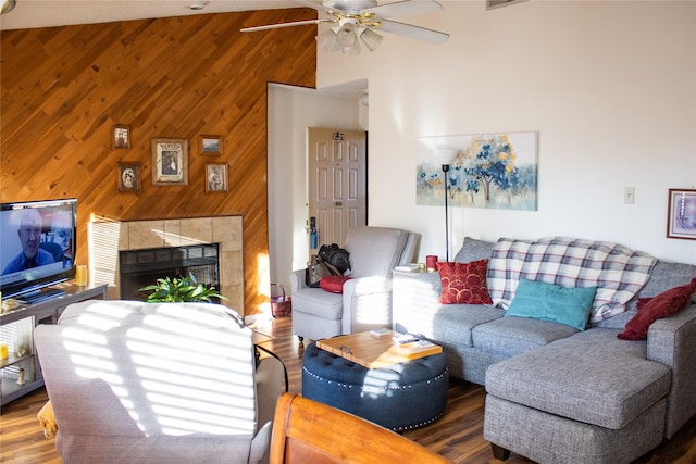 living room featuring a tiled fireplace, wooden walls, ceiling fan, and hardwood / wood-style flooring