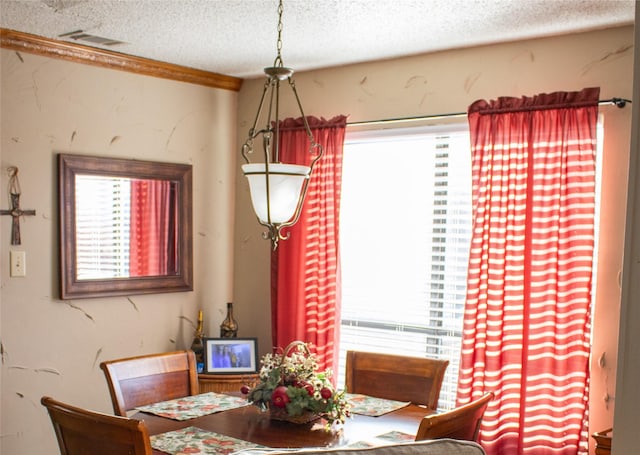 dining area with ornamental molding and a textured ceiling