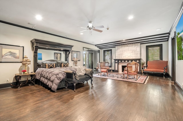 bedroom featuring crown molding, a stone fireplace, and dark hardwood / wood-style flooring