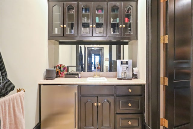 bar featuring sink, dark brown cabinets, and fridge