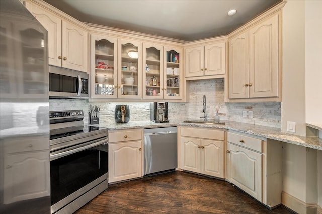 kitchen featuring sink, dark wood-type flooring, stainless steel appliances, tasteful backsplash, and light stone countertops