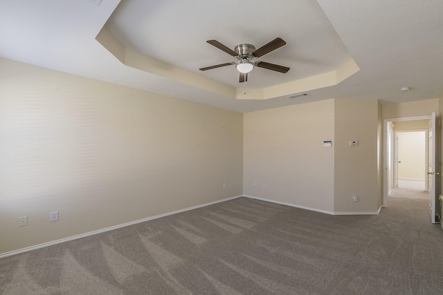 carpeted empty room featuring a raised ceiling and ceiling fan