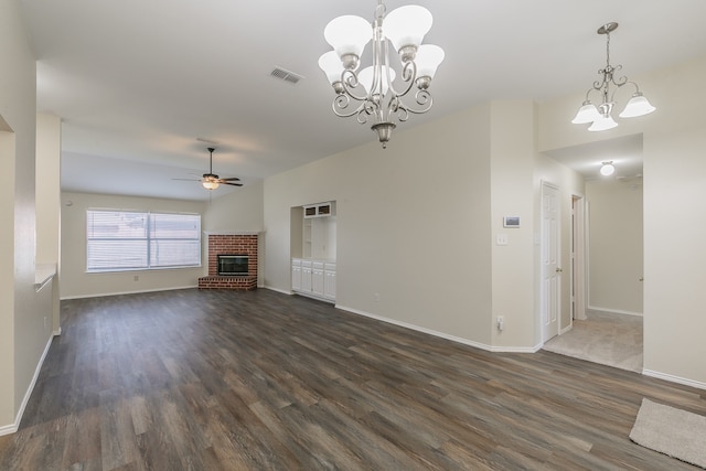 unfurnished living room with ceiling fan with notable chandelier, a fireplace, and dark wood-type flooring