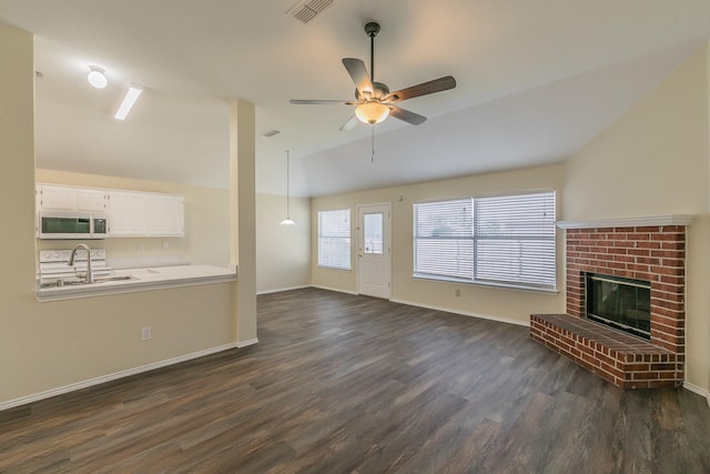 unfurnished living room featuring lofted ceiling, a brick fireplace, dark hardwood / wood-style flooring, and ceiling fan